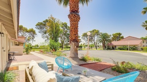A patio with wooden furniture, a blue chair, and a palm tree. - Pool Access & Mtn Views: Palm Springs Retreat! (Palm Springs)