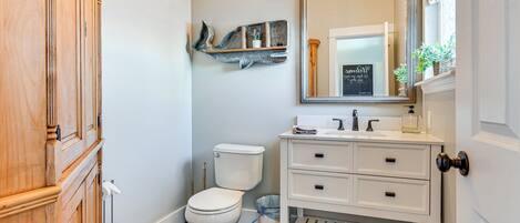A bathroom with a toilet, a sink, and a mirror.