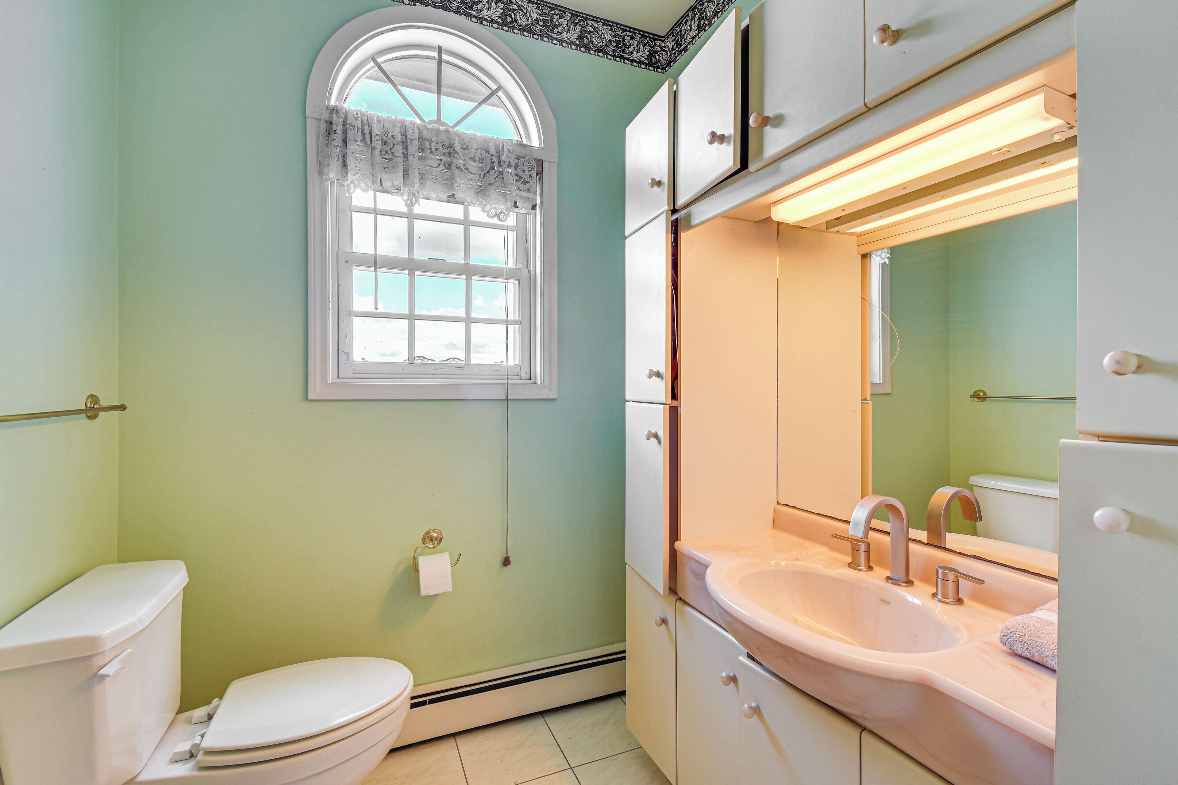 Un baño con inodoro, lavamanos y ventana.