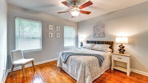 A bedroom with a bed, a chair, a nightstand, a ceiling fan, and wall-mounted pictures. - Large Yard & Fire Pit! Home 13 Mi to At&t Stadium (Fort Worth)