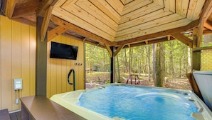 A wooden cabin with a hot tub and a TV mounted on the wall.