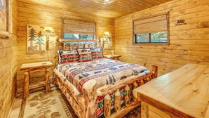 A log cabin room with a bed, wooden walls, and a ceiling light.