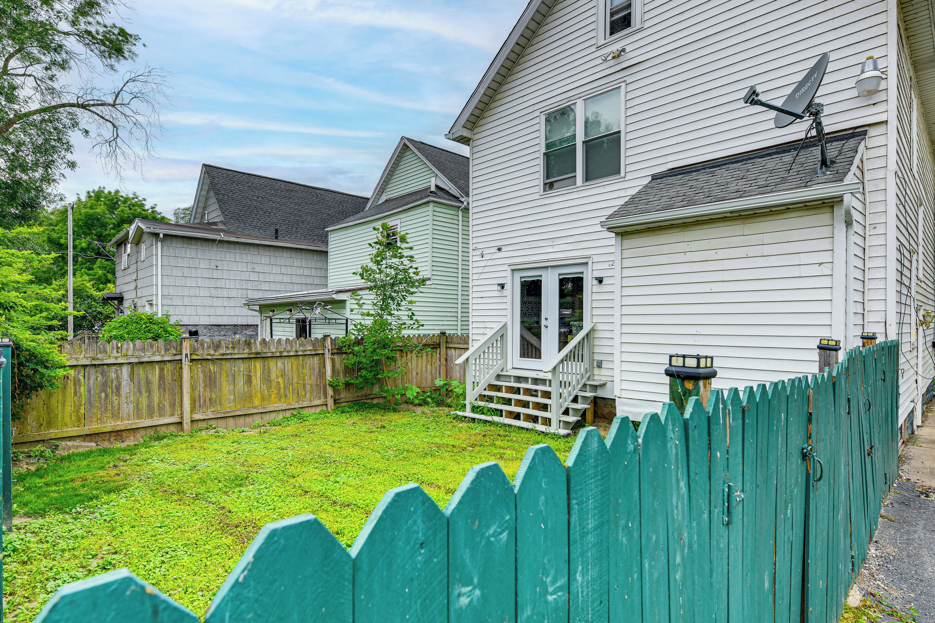 A residential house with a green picket fence, a satellite dish, and a visible front door.