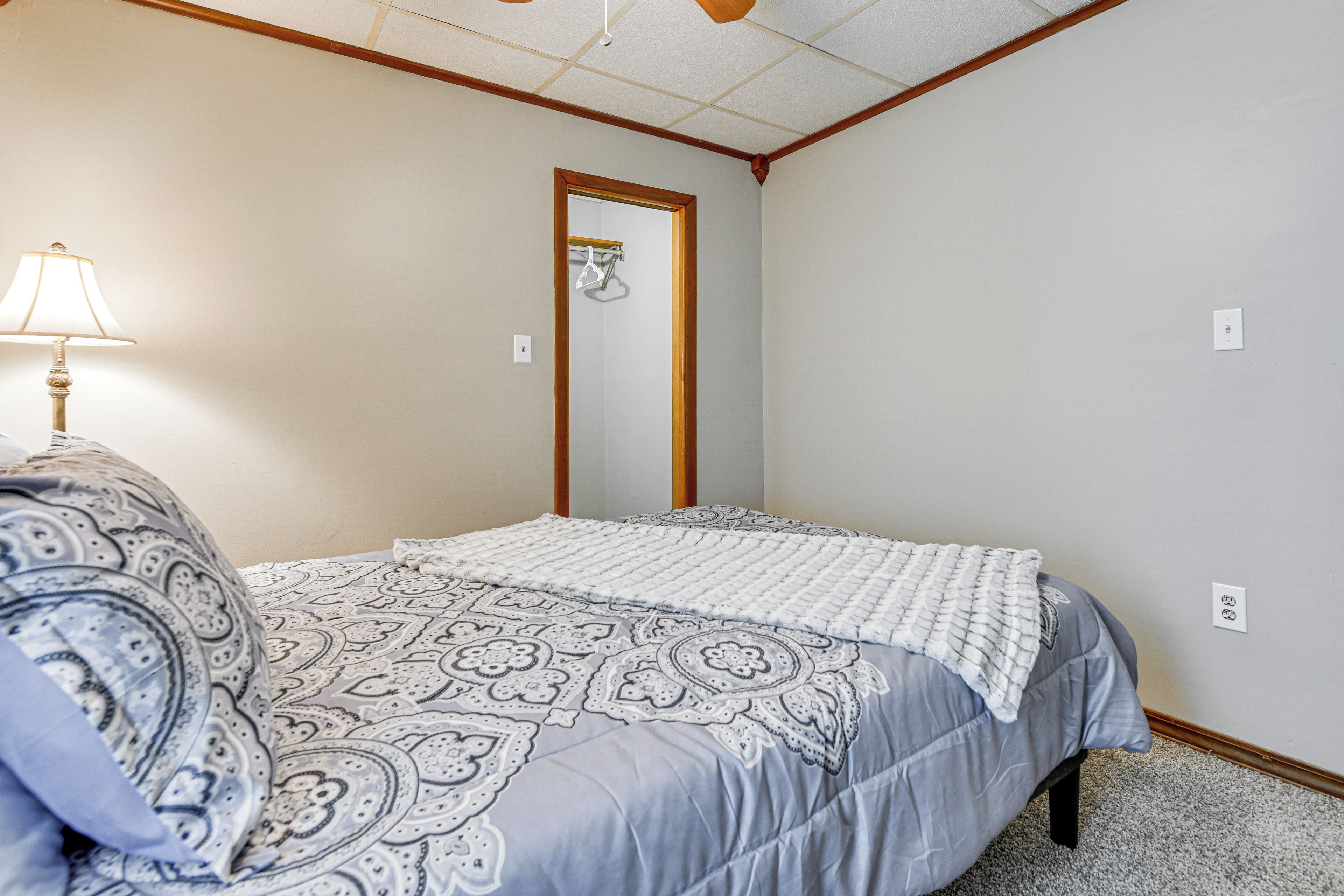 A bedroom with a bed, a nightstand, a lamp, and a mirror.