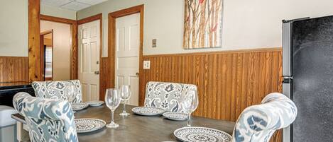 A dining area with a wooden table, patterned chairs, and a black refrigerator.