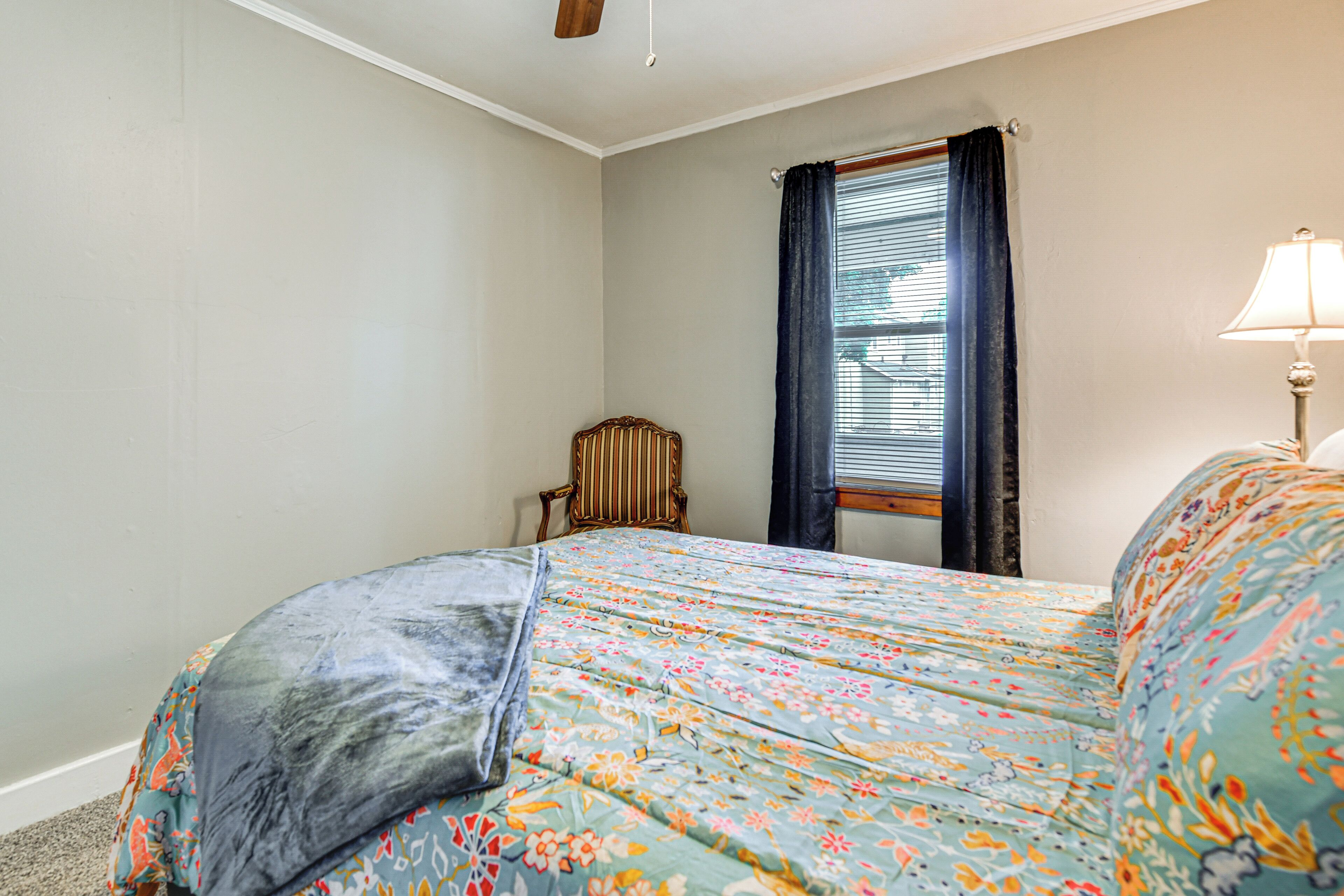 Une chambre à coucher avec un lit, une chaise, une fenêtre avec des rideaux et une lampe.