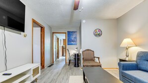 Una sala de estar con televisor, sofá, lámpara y sillón.