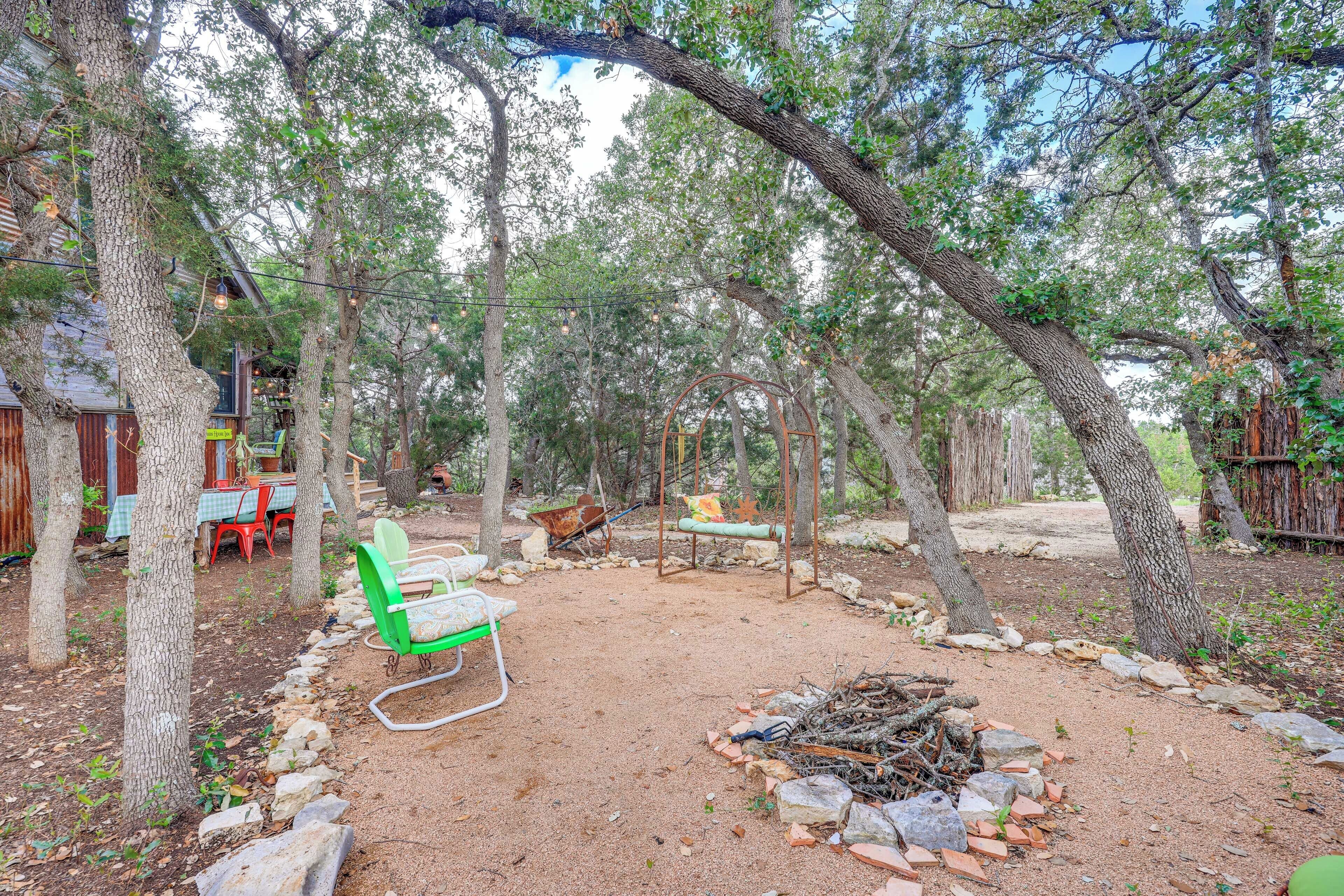 A rustic outdoor area with a dirt ground, a fire pit, and a green chair.