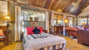 Une chambre à coucher rustique avec un grand lit, des murs en bois et un ventilateur de plafond.