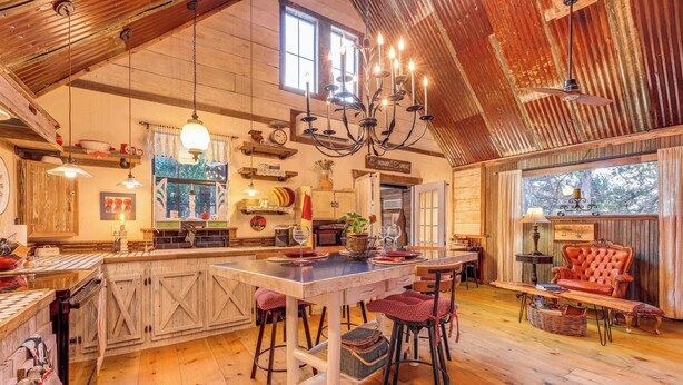 Une cuisine rustique avec des meubles en bois, un grand îlot central doté de tabourets et un lustre.