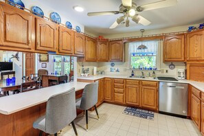 A kitchen with wooden cabinets, a stainless steel dishwasher, and a dining area with a bar. - Peaceful Harrison Home w/ Porch & Grill! (Harrison)