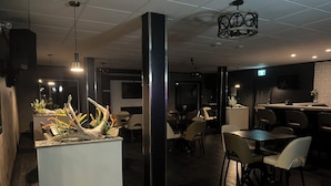 Un interior de restaurante moderno con una isla central, mesas, sillas y una zona de bar.