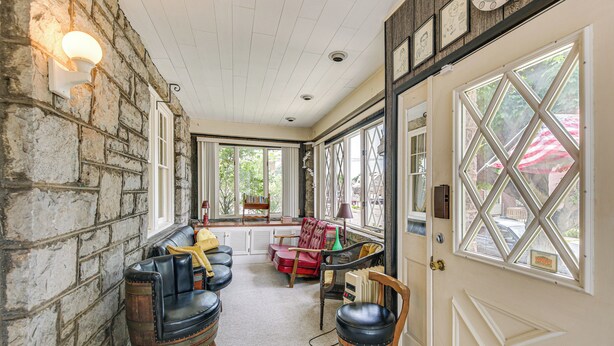 A cozy room with stone walls, a wooden door, and large windows. There are leather chairs and a red sofa. - 15 Mi to Seven Springs Resort: Somerset Home! (Somerset)