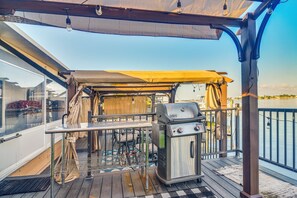 An outdoor deck with a grill, a table, and a covered area. - Bayfront St Petersburg Home w/ Hot Tub & Dock! (St. Petersburg)