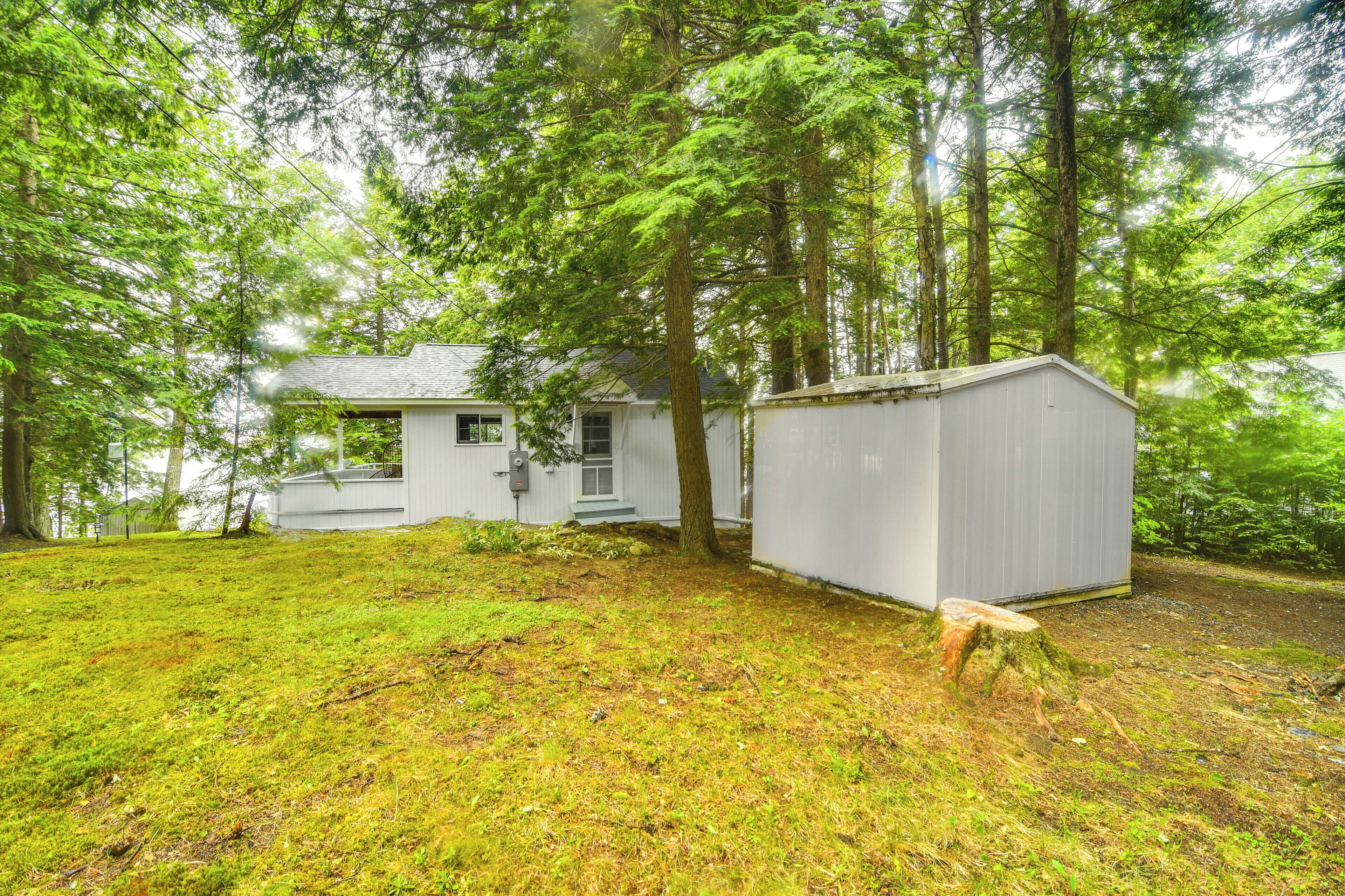 A white house with a small shed in a forested area.