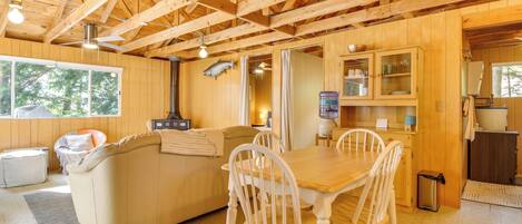 Interior de una cabaña de madera con comedor, sofá y cocina.