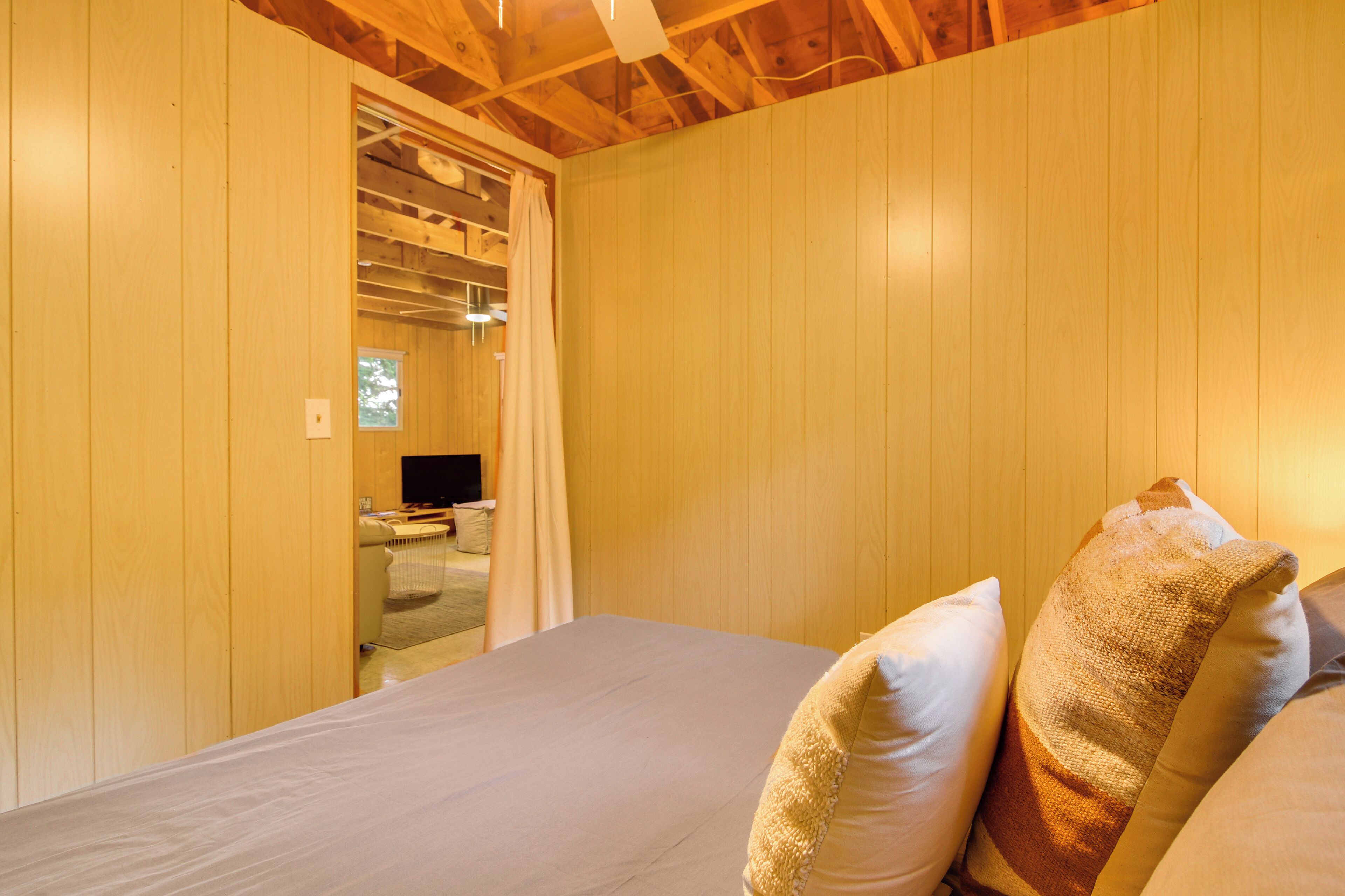 A room with wooden walls, a bed with two pillows, and a television in the background.