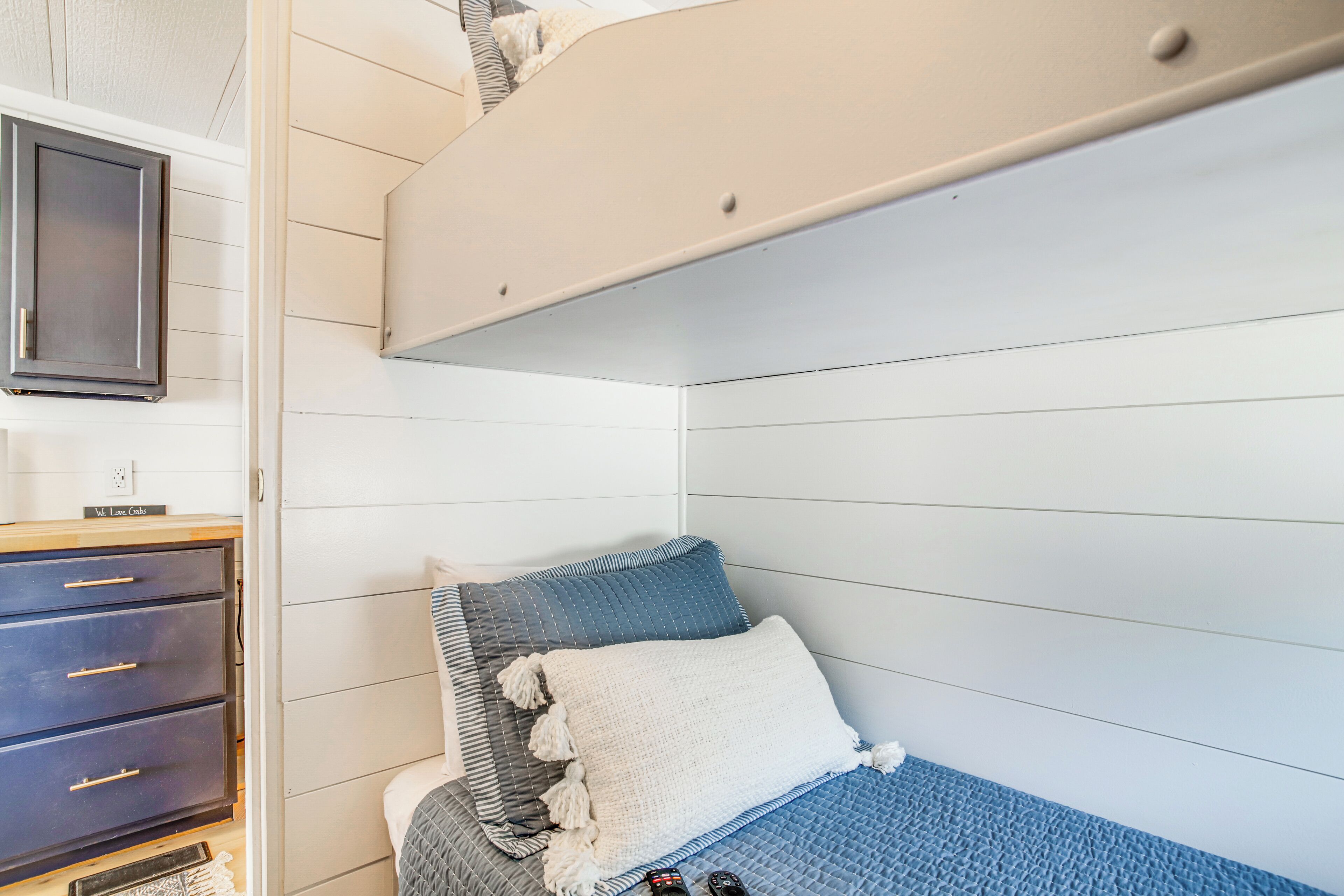 Une chambre avec un lit superposé, une commode et une table de chevet.
