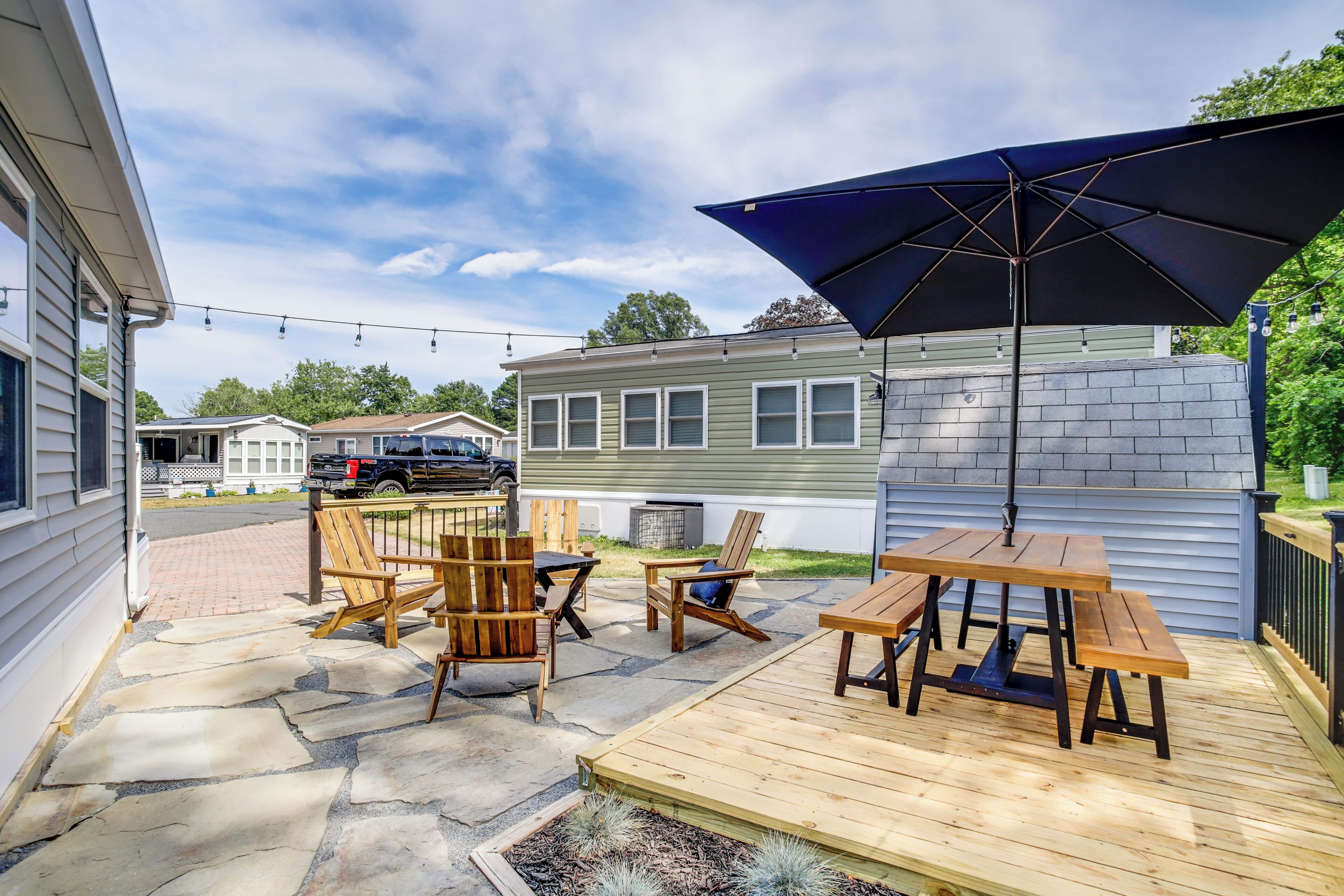 Une terrasse avec des meubles en bois, une table et un parasol.