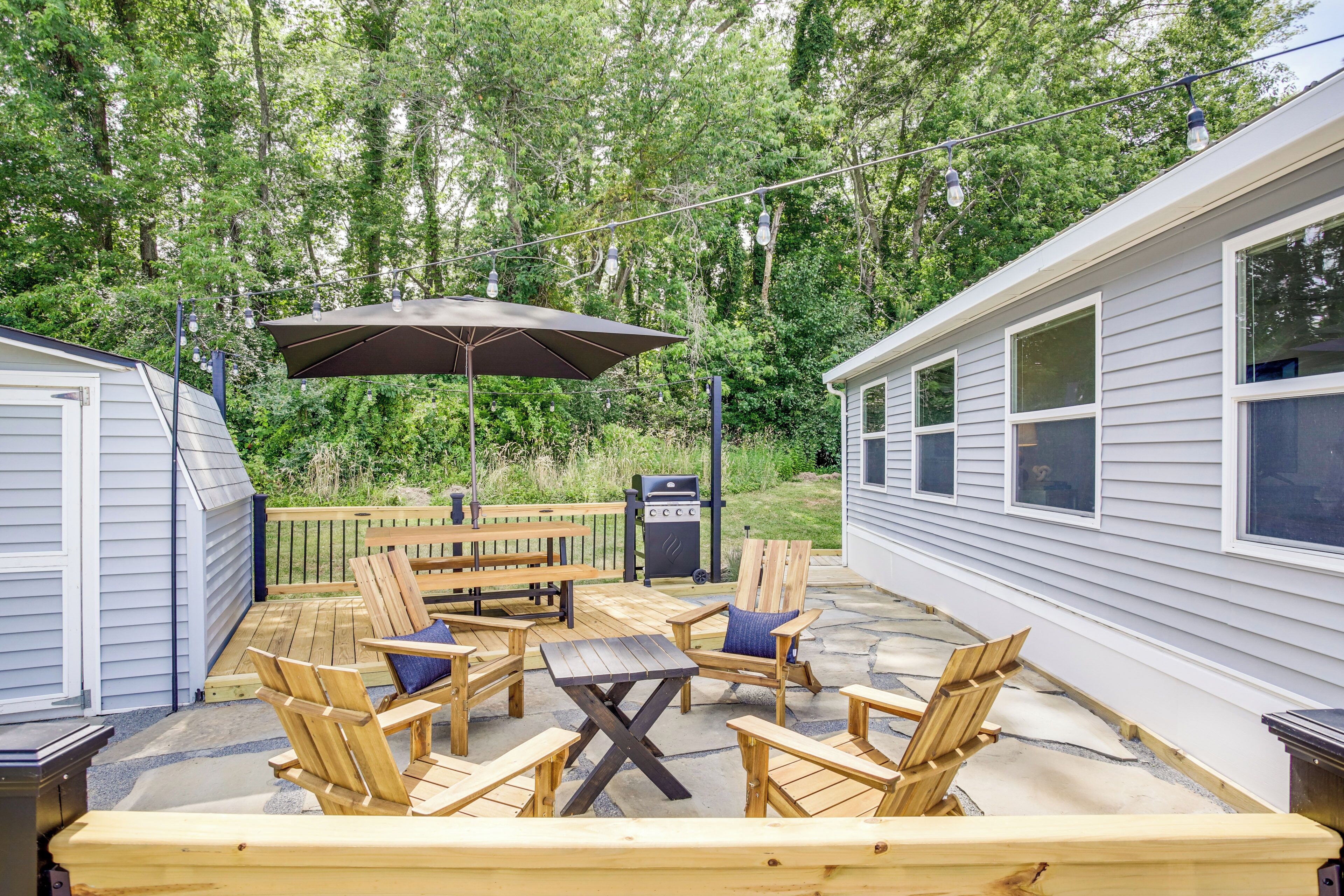 A wooden deck with outdoor furniture, a grill, and a string of lights.