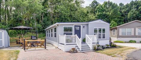 Une petite maison mobile de plain-pied, dotée d’un porche et d’un espace patio.