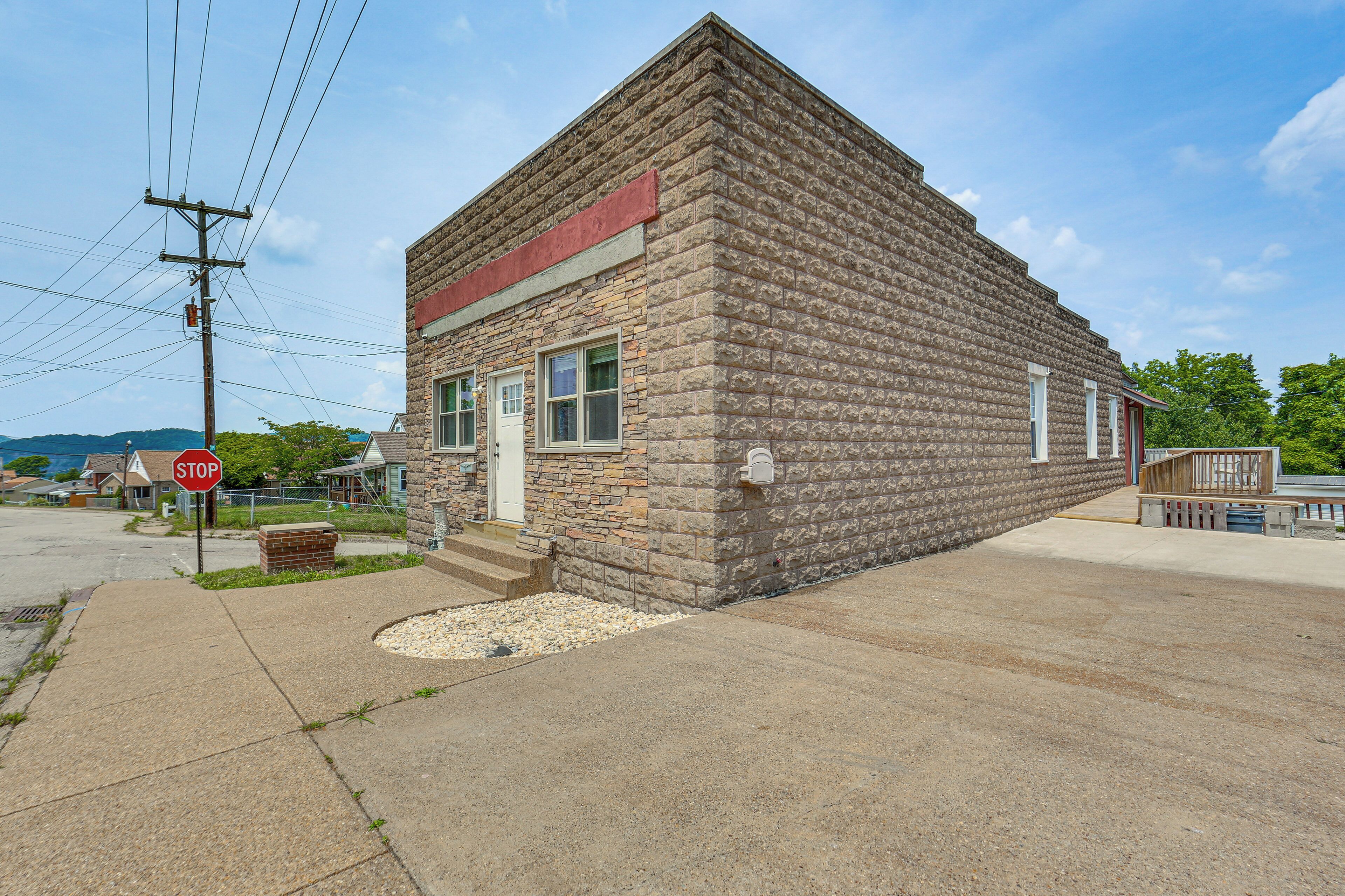 A small, stone building with a red roof, a stop sign, and a mailbox.