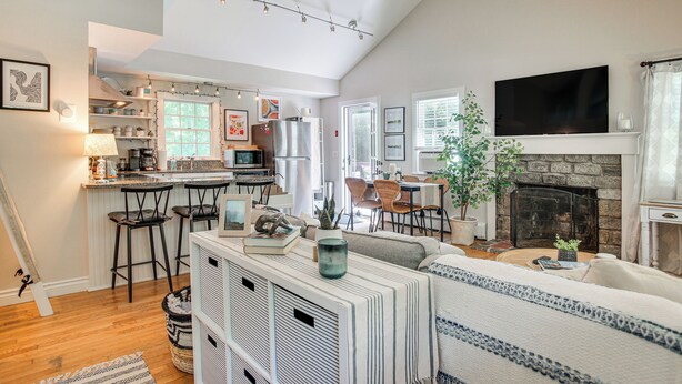 Un amplio salón con chimenea, una cocina con taburetes de bar y un comedor con mesa y sillas.