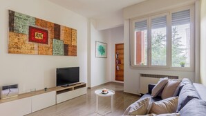 Ett modernt vardagsrum med en platt-TV, ett soffbord, en soffa och en bokhylla.