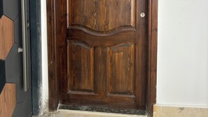 Una puerta de madera con un picaporte de metal y cerradura, en un ambiente con suelo de baldosas.