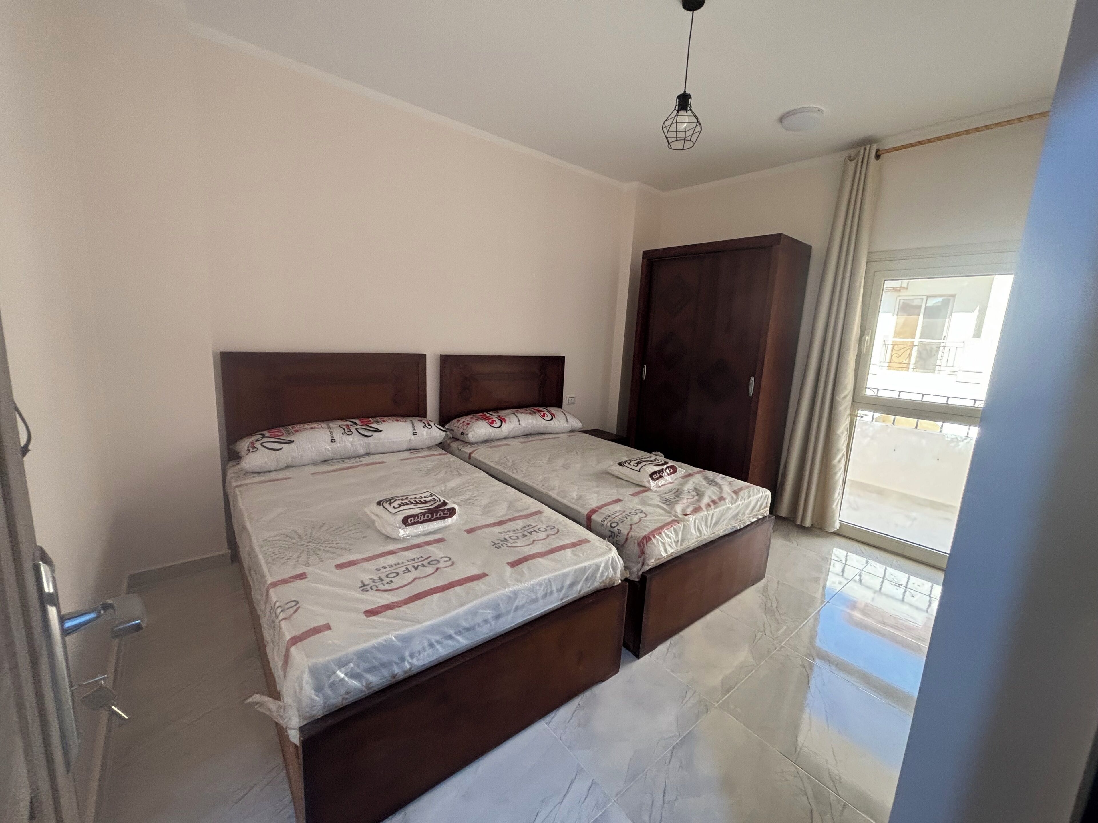 Un dormitorio con dos camas, un armario y un balcón.