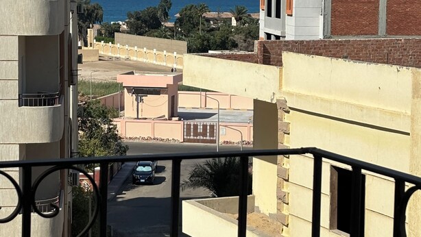 Un balcón con vista al mar, edificios y un estacionamiento.