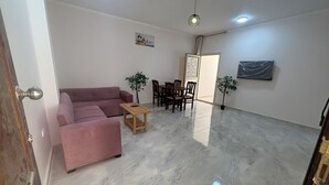 Un salón amplio con un sofá rosa, una mesa de centro de madera y un comedor con sillas y una mesa.