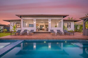A two-story house with a pool, outdoor seating, and a covered patio. - Island Villa + Guest House | Pool, Hot Tub, Fire Pit, Hammock & Ocean Views (Koloa)