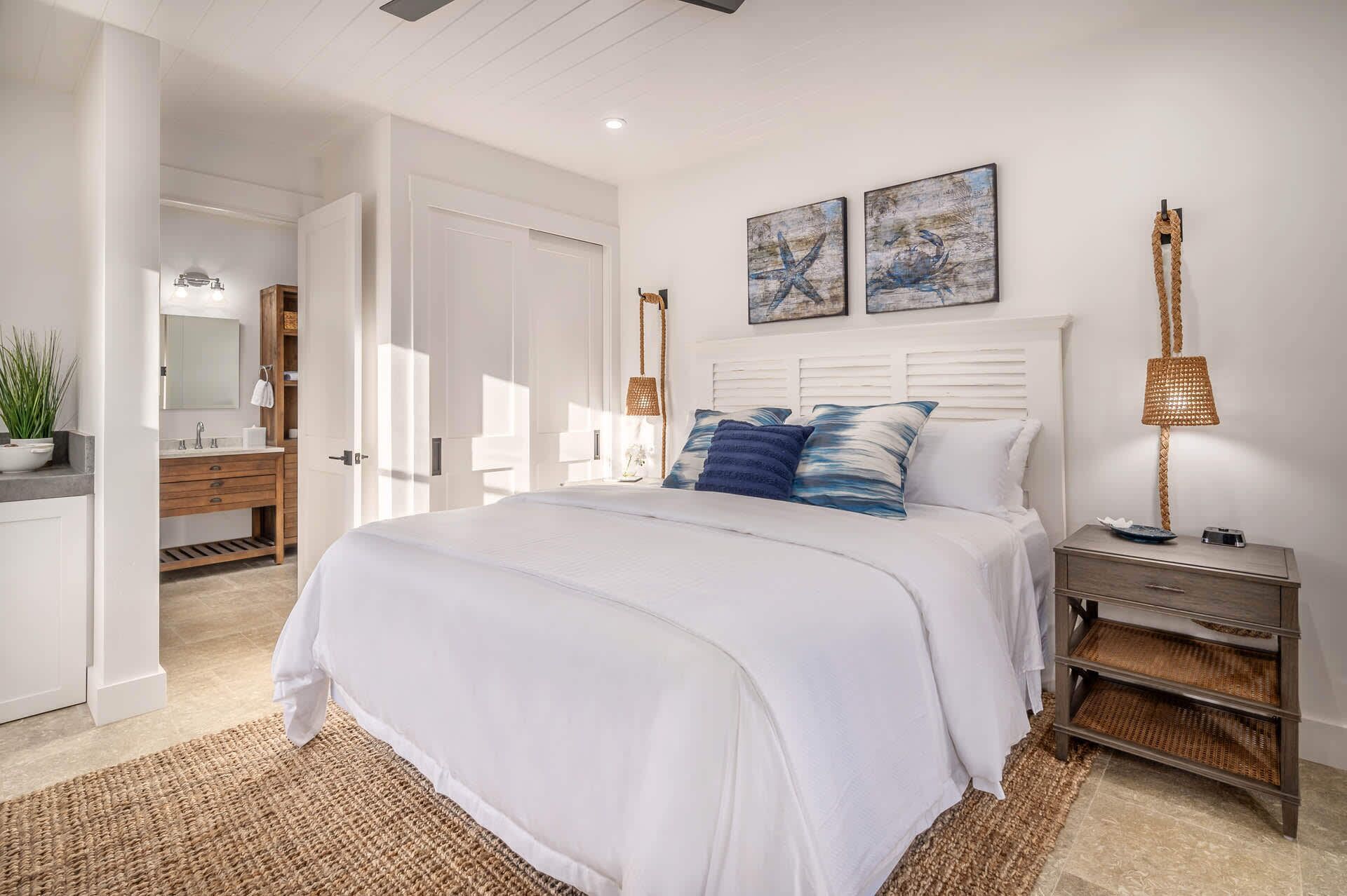 A bedroom with a large bed, a nightstand, a lamp, and a dresser.