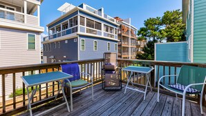 Una terraza de madera con mobiliario exterior y vistas a edificios de varios pisos.