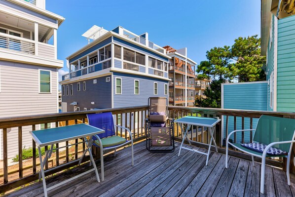 A wooden deck with outdoor seating and a view of multi-story buildings.