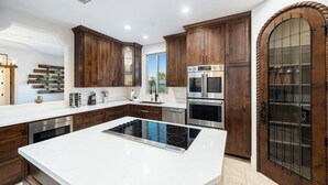 Una cucina moderna con mobili in legno scuro, elettrodomestici in acciaio inossidabile e un'isola centrale con piano cottura a induzione.