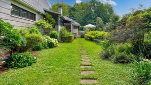 A house with a well-maintained garden, a stone pathway, and outdoor furniture.
