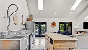 A modern kitchen with stainless steel appliances, a wooden island, and a view to the outdoors.