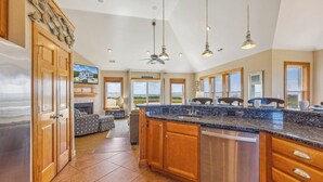 A spacious kitchen with wooden cabinets, a stainless steel dishwasher, and a large island with a sink. - Soundfront Home w/ Indoor Pool, Hot Tub, Elevator, Game Room, Tiki Bar, Theater (Avon)