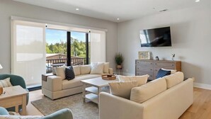 A modern living room with a sofa set, a coffee table, and a TV mounted on the wall. - Walloon Village 1 Bedroom Condo Across From The Lake! 7 night minimum. (Walloon Village)