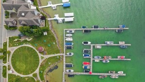 An aerial view of a marina with boats docked in rows, a parking area, and a building with a flat roof. - Walloon Village 1 Bedroom Condo Across From The Lake! 7 night minimum. (Walloon Village)