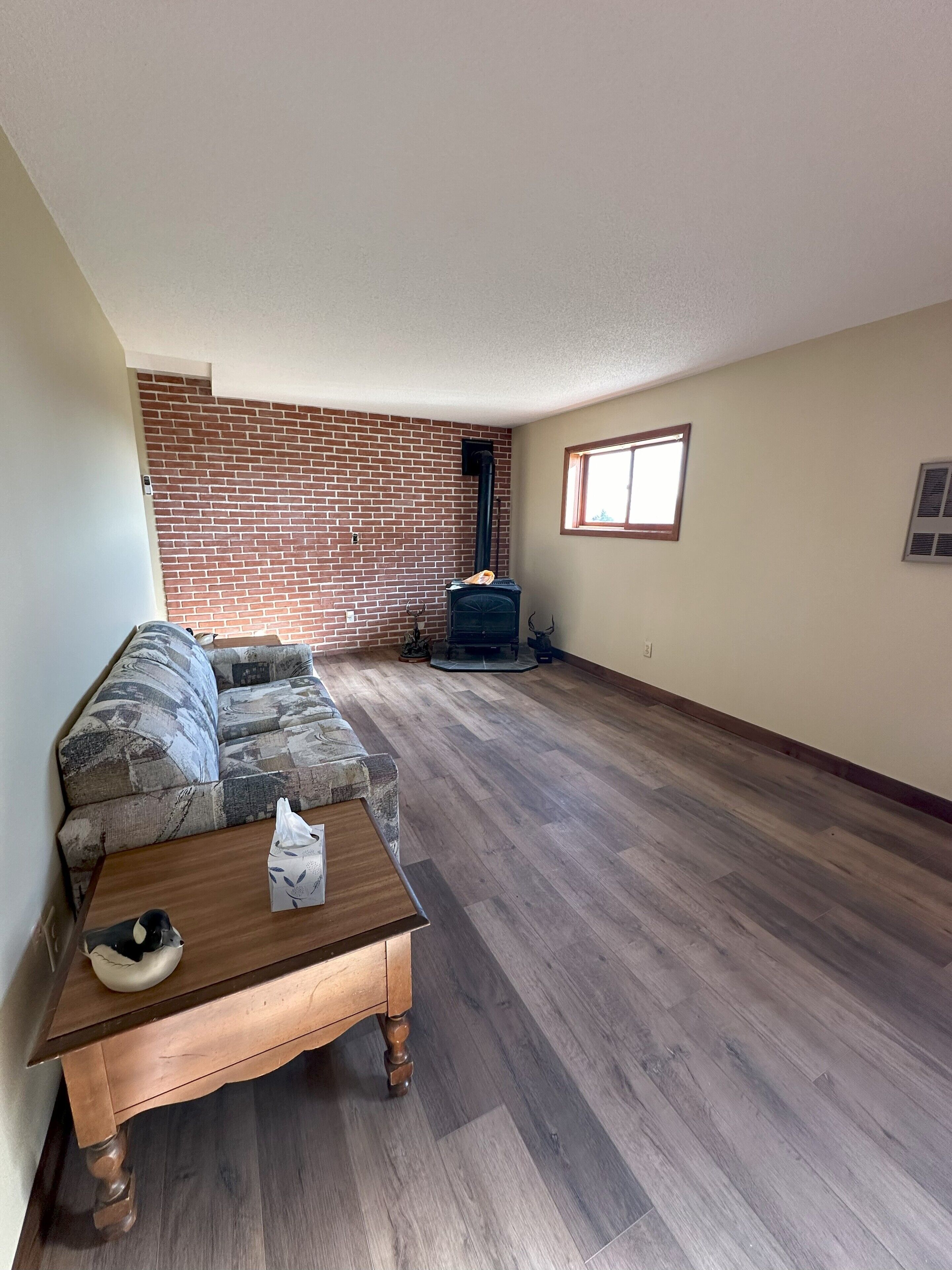 Una sala de estar con pared de ladrillo, chimenea, sofá y mesa de centro de madera.