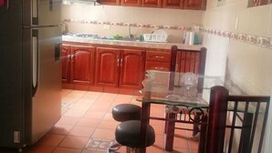 A kitchen with wooden cabinets, a refrigerator, a glass table, and a chair. - Enjoy the historical center of Cali  (Cali)