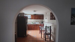 A kitchen with wooden cabinets, a refrigerator, and a dining area with chairs and a table. - Enjoy the historical center of Cali  (Cali)