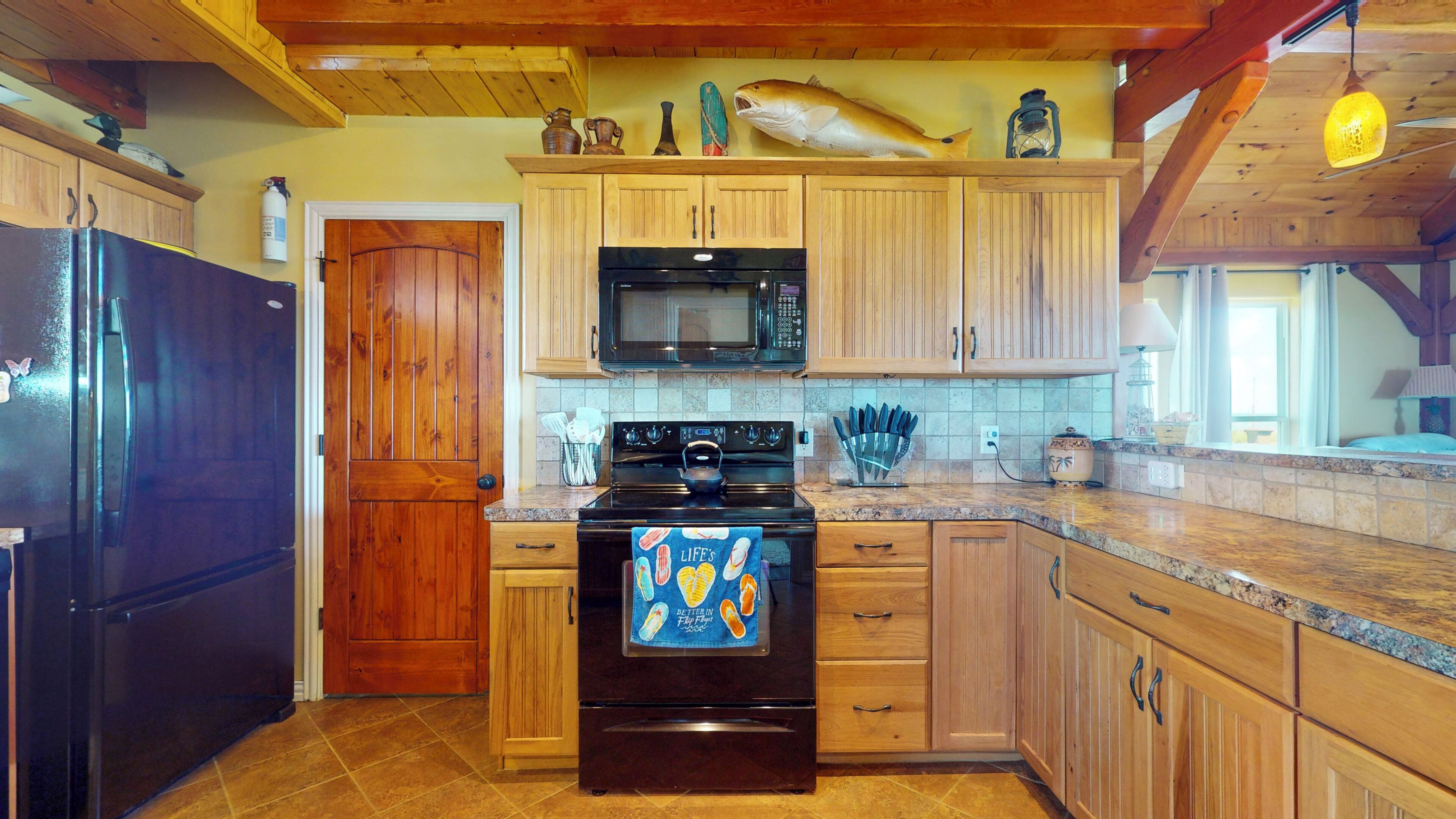 A kitchen with wooden cabinets, a black refrigerator, a microwave, and a stove.