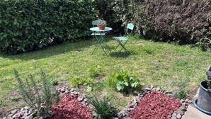 Een tuin met een mulchbed in de vorm van een hart, een tafeltje en een stoel.