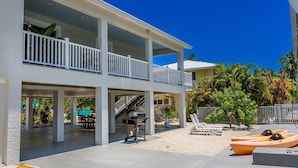 Un bâtiment à deux étages doté d’un patio couvert, d’un espace extérieur aménagé pour s’asseoir et offrant une vue sur la végétation tropicale environnante.