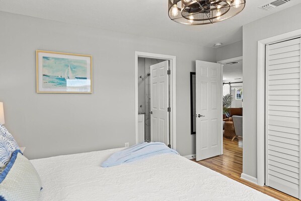 A bedroom with a bed, a framed painting, and a hallway leading to another room. - Take it Keysie, Waterfront House (Marathon)
