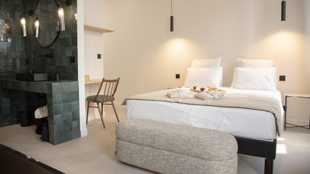 A modern bedroom with a bed, bedside tables, a chair, and a bench. - Mouchki (Marseille)